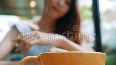 <strong>活泼开朗</strong>的亚洲年轻女人在咖啡馆里喝着热咖啡或茶享受着它。